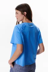 Remera blanca de manga corta con detalle de encaje floral en el hombro.