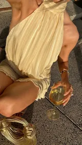 Minivestido color crema con cuello halter, espalda descubierta y falda con volados.