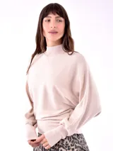 Buzo color beige de tejido acanalado, con cuello alto y manga larga amplia.