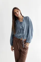 Camisa celeste de voile de algodón con cuello a la base y mangas balloon. Cierre frontal con lazos en la misma tela.