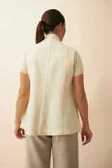 Chaleco color beige, entallado, con solapa, bolsillos plaqué y terminaciones envivadas.