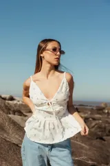 Blusa blanca con estampado floral, de tirantes finos, escote en V con lazo ajustable y corte peplum.