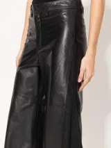 Pantalón de cuero vacuno negro, de silueta amplia con recortes diagonales en delantero y espalda. Tiene un complemento de lino al tono aplicado en los laterales.