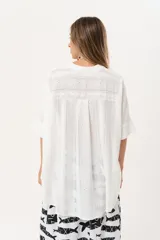 Camisa blanca con calados, escote en V, abotonada y manga 3/4.