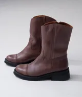 Bota de cuero vacuno color marrón, con caña media, suela de caucho y punta redonda.