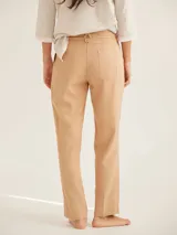 Pantalón cigarette color beige, de corte recto y tiro medio, con bolsillos laterales y cierre frontal con botón y cremallera.