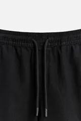 Bermuda negra regular fit confeccionada en tejido de algodón con estructura. Cintura elástica ajustable con cordón, bolsillos laterales y bolsillo trasero de vivo.