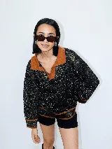 Buzo negro con cuello polo y calado, tejido a máquina con hilado serido y lurex, de estilo oversized.