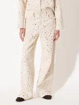 Pantalón wide jeanero color crudo con agujeros desflecados y flecos en los bolsillos.