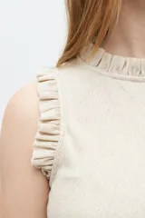 Top de tejido de punto gris con rayas verticales negras, cuello alto con volados y volados en las sisas.