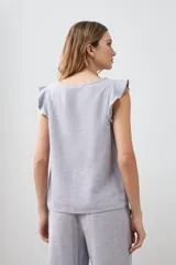 Blusa gris melange sin mangas con volados en los hombros y vivo metálico.