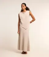 Blusa de punto color beige, sin mangas, con escote redondo y bajo asimétrico.
