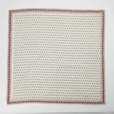Pañuelo cuadrado de tela fina color crema con estampado de flores pequeñas en rojo y negro.