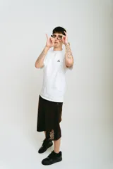 Bermuda de jean color marrón con lavado gastado, corte baggy, bolsillos grandes y bordados ornamentales en los laterales.