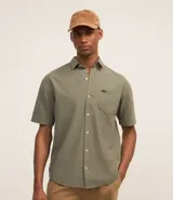 Camisa de hombre de corte relajado, color crudo, con cuello inglés, mangas cortas, abotonado delantero, bolsillo en el pecho y etiqueta de la marca.