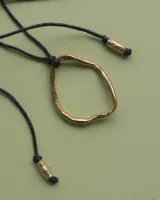 Collar con dije circular irregular de alpaca y plata 925, con hilo de algodón natural.