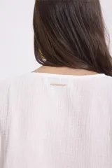 Blusa blanca de manga larga con escote en V y lazos para atar en el frente.