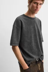 Camiseta color gris verdoso de punto tejido en hilatura de algodón, con cuello redondo, manga corta, efecto lavado y acabados irregulares.