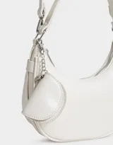 Bandolera color blanco crudo de cuerina, con asa de hombro y pouch lateral con cierre y charm de metal.