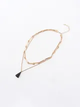 Collar doble dorado con cadena de eslabones grandes y cadena fina con dije colgante triangular negro.