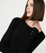 Suéter de punto color verde, con cuello barco, mangas largas y textura acanalada.