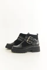 Botas cortas negras de cuero con punta cuadrada, detalle de hebilla metálica y suela track.