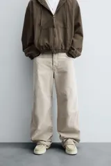 Pantalón de jean color beige, de corte amplio y tiro alto, con cinco bolsillos, efecto lavado y cierre frontal con botones.