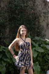 Vestido corto negro con escote en V, breteles finos cruzados en la espalda, abertura en la cintura y falda con volados.