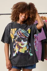 Remera negra con efecto acid wash, corte holgado y estampa frontal de una mujer con gafas de sol.