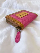 Billetera pequeña con cierre metálico, cuerpo principal en tejido texturizado color fucsia y detalles en cuero marrón con textura de reptil. Posee un parche de cuero claro con la palabra "chowie" escrita a mano.