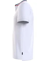 Chomba blanca de corte slim con cuello mao, tapeta de tres botones y logo de Tommy Hilfiger bordado en el pecho. El cuello presenta una banda con los colores característicos de la marca: azul marino, blanco y rojo.