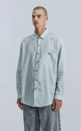 Camisa manga larga verde agua con bolsillo en el pecho, de calce oversize confeccionada en textil plano fresco y liviano.