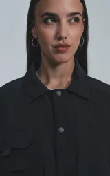 Campera negra oversize con broches en el delantero, forrada con red, múltiples bolsillos con detalles réflex y puños elásticos.