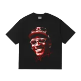 Remera oversize negra con estampado gráfico en rojo y blanco de Michael Jordan sonriendo, usando una gorra de béisbol con la palabra "CHAMPIONS" y gafas de sol. Incluye una firma estilizada en rojo en la parte inferior del gráfico.