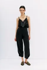 Pantalón sastrero negro de tiro alto confeccionado en cupro y viscosa, con ajuste en el tobillo, bolsillos delanteros y traseros, y pinzas en el frente.