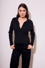 Cardigan negro de punto con cuello polo, manga larga y cierre frontal con botones.