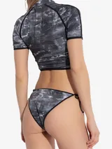 Top de bikini Diesel con estampado abstracto en tonos grises y blancos, cierre frontal con cremallera y logo rojo en el pecho.
