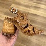 Sandalias de cuero color marrón con diseño de tiras geométricas y taco de madera.