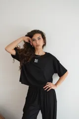 Remera negra de manga corta y corte holgado, con un pequeño logo bordado en blanco en el pecho.