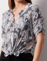 Blusa de gasa estampada color celeste con estampado paisley, marca Ruby Rd. Cuello a la base, escote en v y abertura con botones. Delantera con bolsillos. Largo de manga regulable con presilla y botón. Terminación de ruedo con nudo.