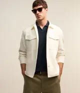 Campera trucker masculina de jeans color crudo, con cuello solapa, abotonado delantero, bolsillos con solapa y superficie lisa.