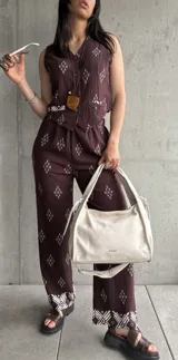 Conjunto de chaleco y pantalón color chocolate con estampado de rombos blancos. Chaleco con botones y pantalón de corte recto con elástico en la cintura y detalle de guarda pampa en el ruedo.