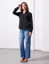 Camisa blanca de manga larga con cuello con solapa y abertura central con botones. Delantera con bolsillos aplicados.
