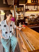 Camisa blanca con bordados de flores negras, de corte oversized y mangas cortas.