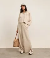Campera deportiva color beige con rayas verticales finas, corte oversized, capucha con cordón ajustable, cierre frontal con cremallera, estampa bordada en el pecho, mangas largas ajustadas y bajo ajustado.