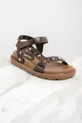 Sandalias marrones de cuero con suela gruesa y tachas doradas en forma de estrella y circulares.