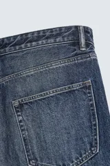 Pantalón de jeans de algodón, corte baggy fit, tiro medio, con efecto lavado en tonos grises y verdes. Presenta cinco bolsillos y cierre frontal con cremallera y botón.