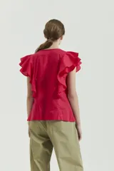 Top de voile liso color fucsia, sin mangas, con escote redondo y tajo pequeño en el centro. Tiene detalle de alforzas finas a cada lado del tajo y dos volados superpuestos que continúan de adelante hacia atrás.