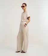 Pantalón de mujer de tiro alto, corte wide leg, color beige con finas rayas verticales en tono oscuro. Presenta cintura elástica fruncida y caída fluida.