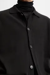 Camisa de punto color negro, corte relaxed fit, con cuello solapa, manga larga y cierre frontal con botones.
